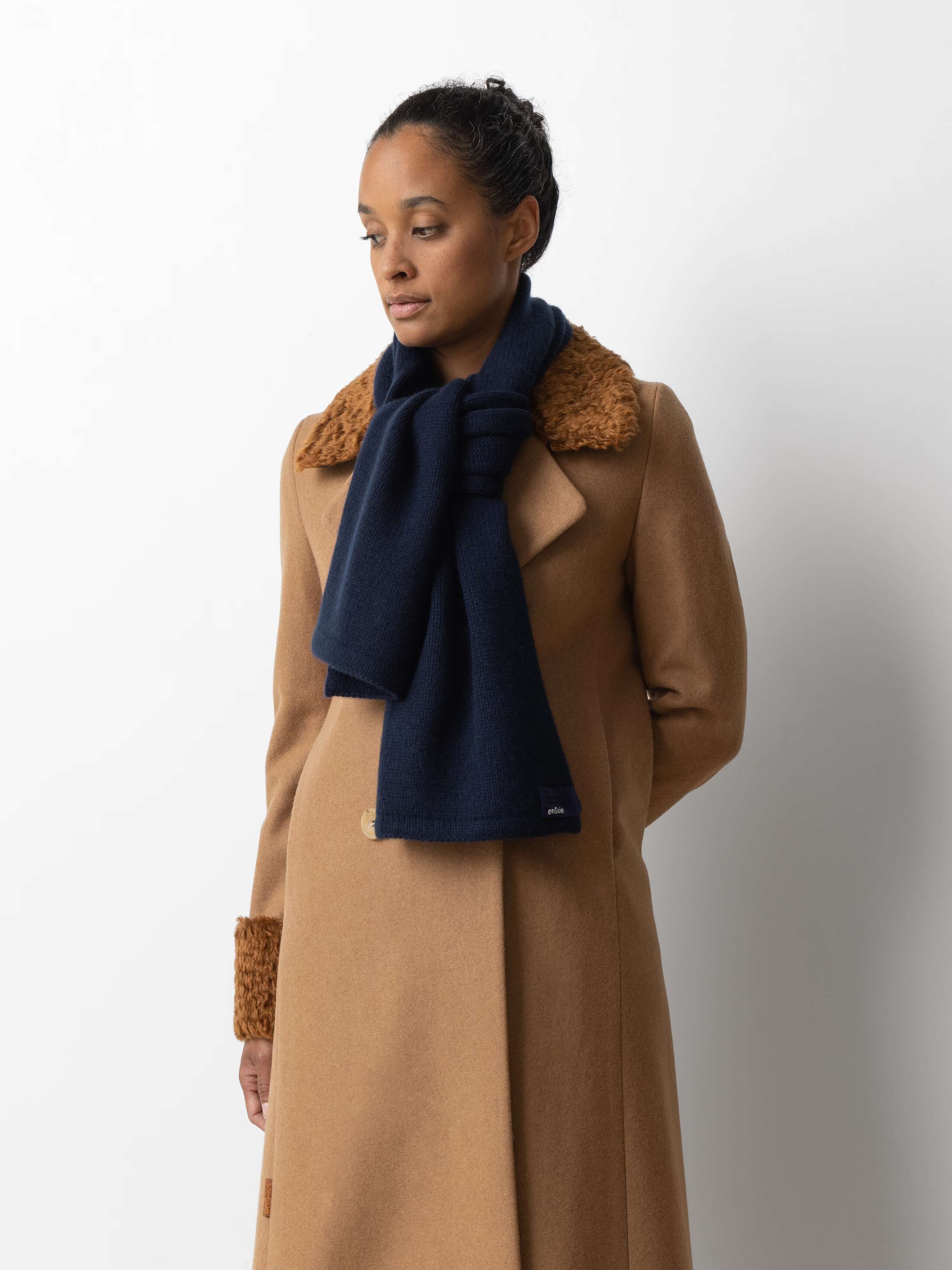Picture of a female model wearing a beige winter coat in combination with a navy blue cashemre scarf