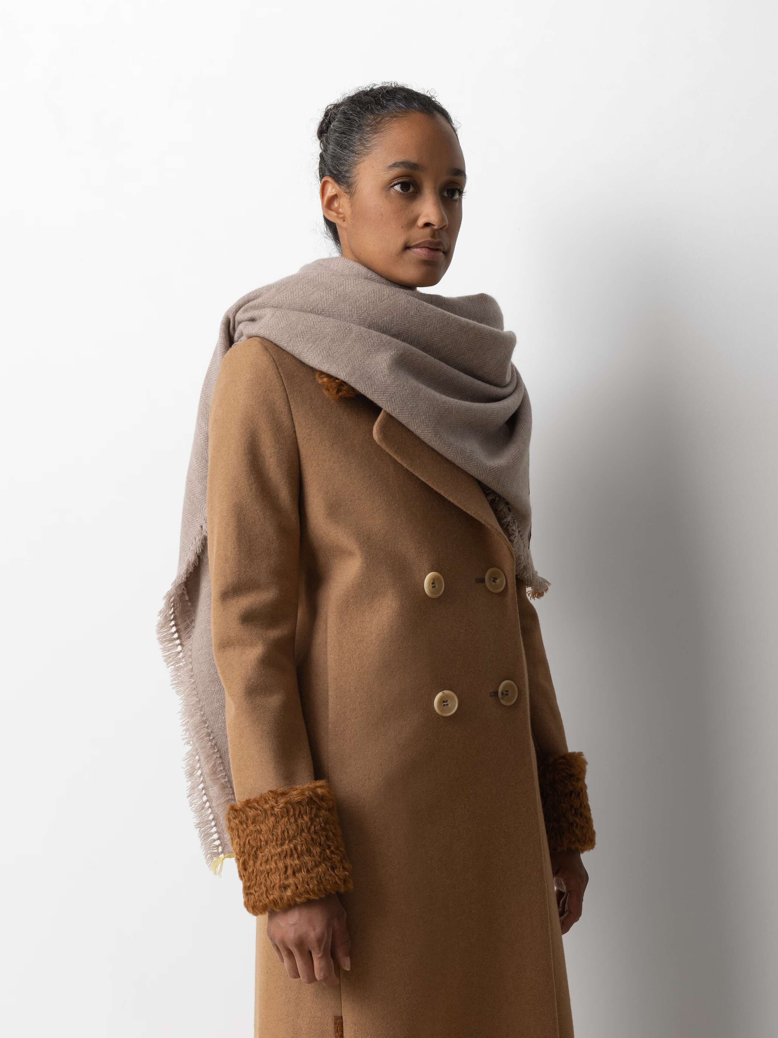 Picture of a female model wearing a beige wool coat and a beige cashmere stole