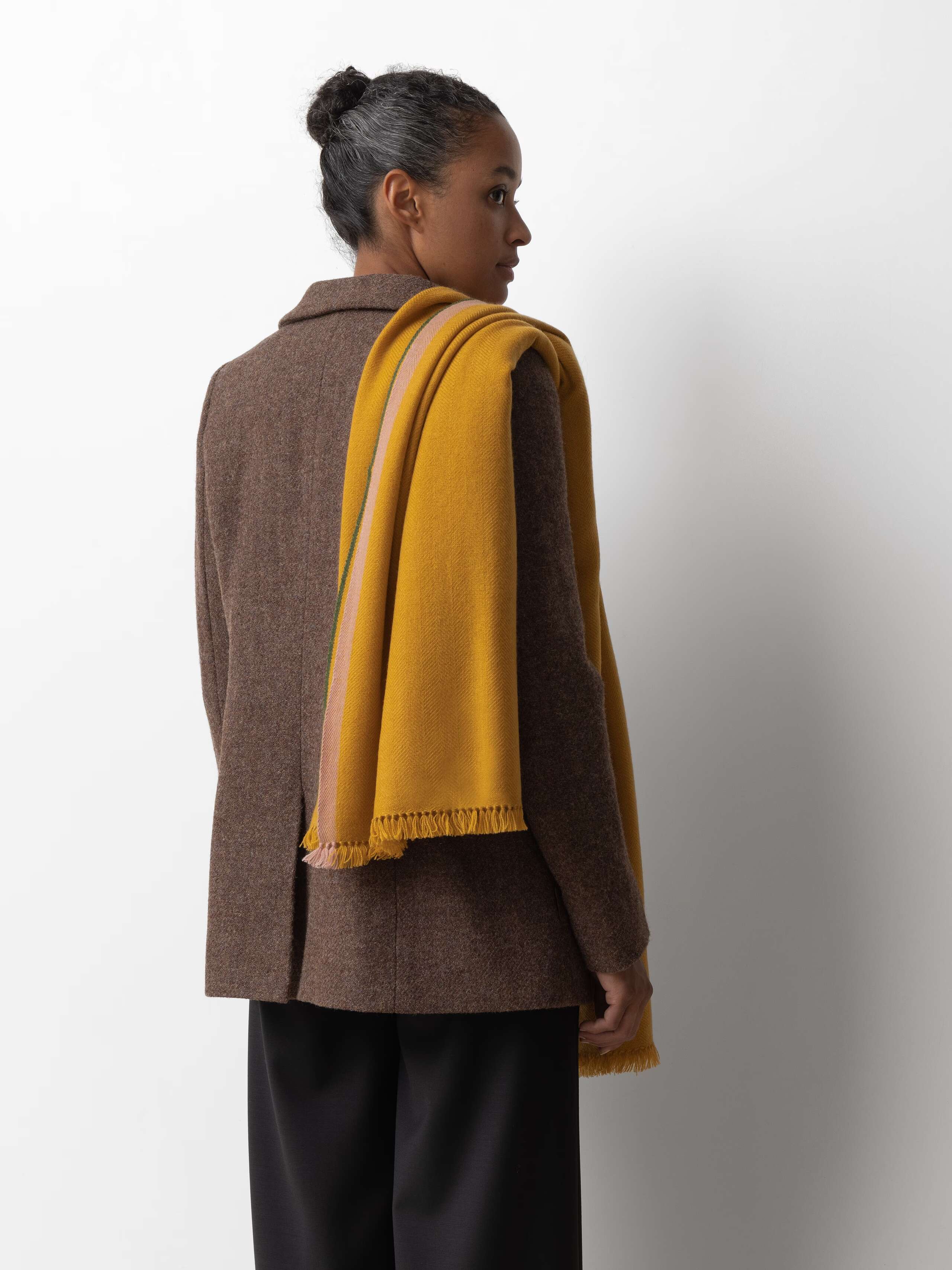 Picture of a female model wearing a brown wool blazer in combination with a yellow cashmere stole