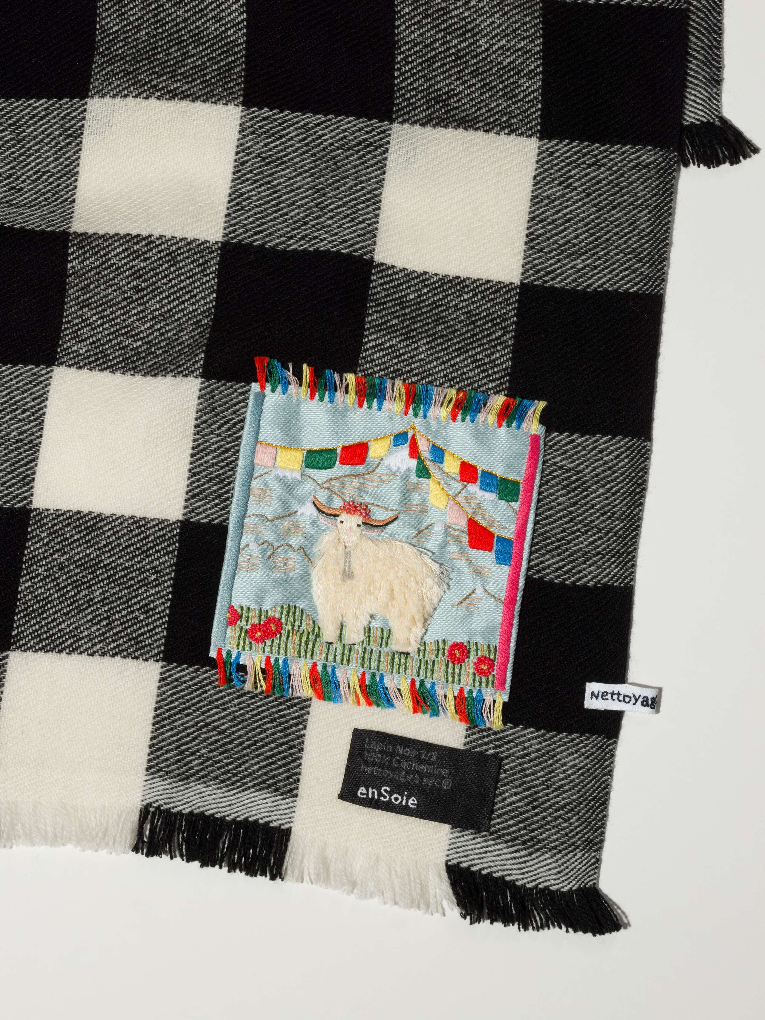 Picture of a detail of a cashmere scarf featuring a black and white check pattern