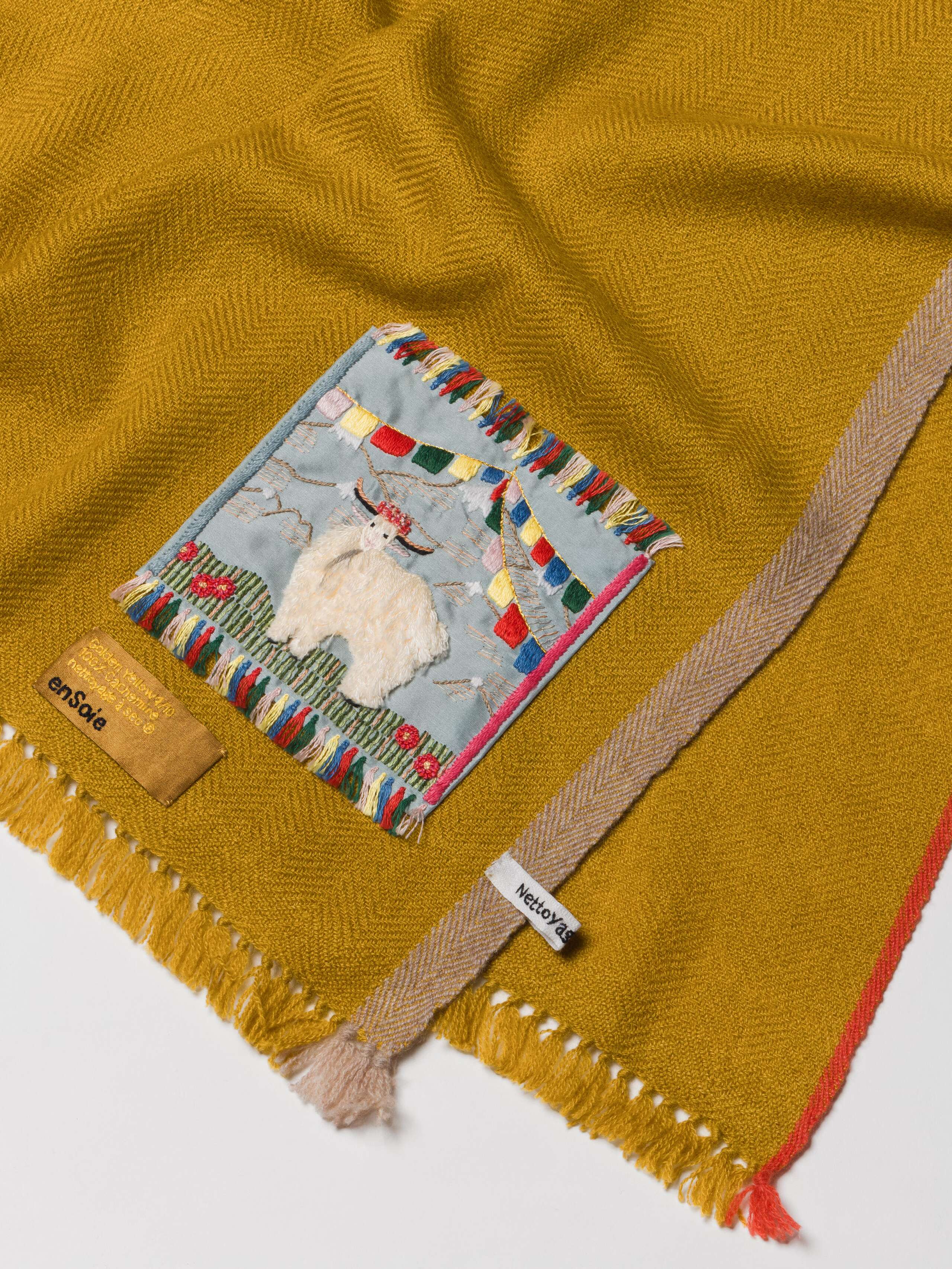 Picture of a detail of a cashmere stole in a warm yellow shade
