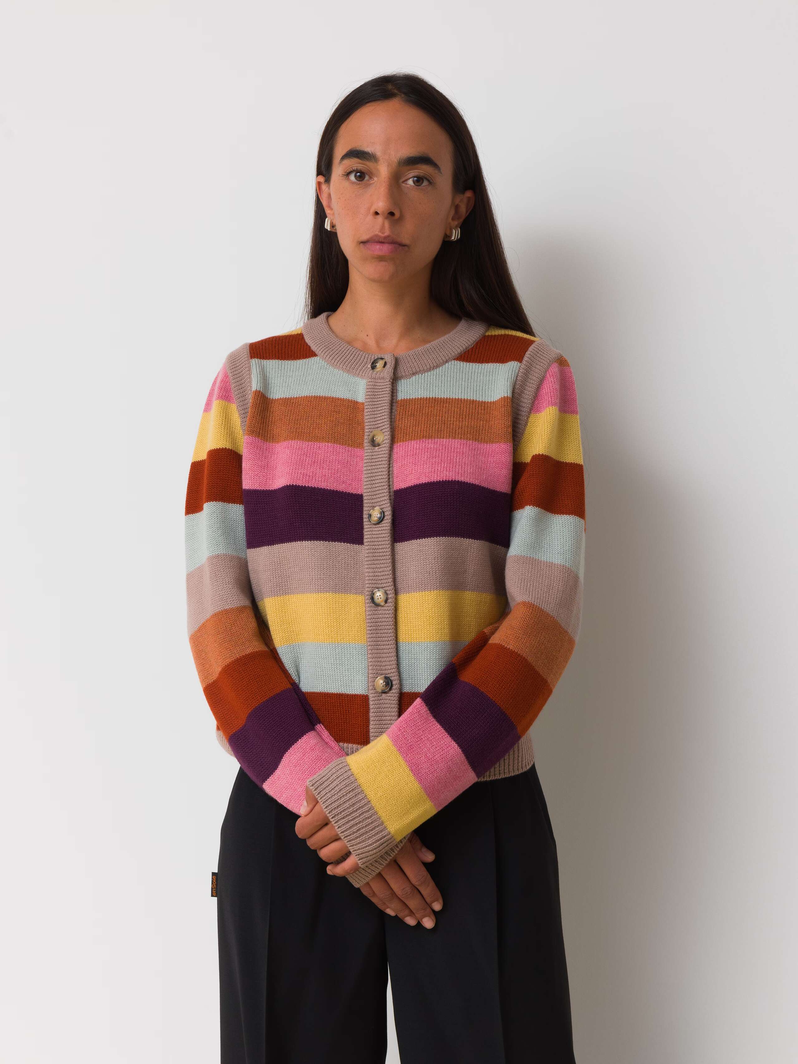 Female model is wearing a colourfully striped merino wool cardigan