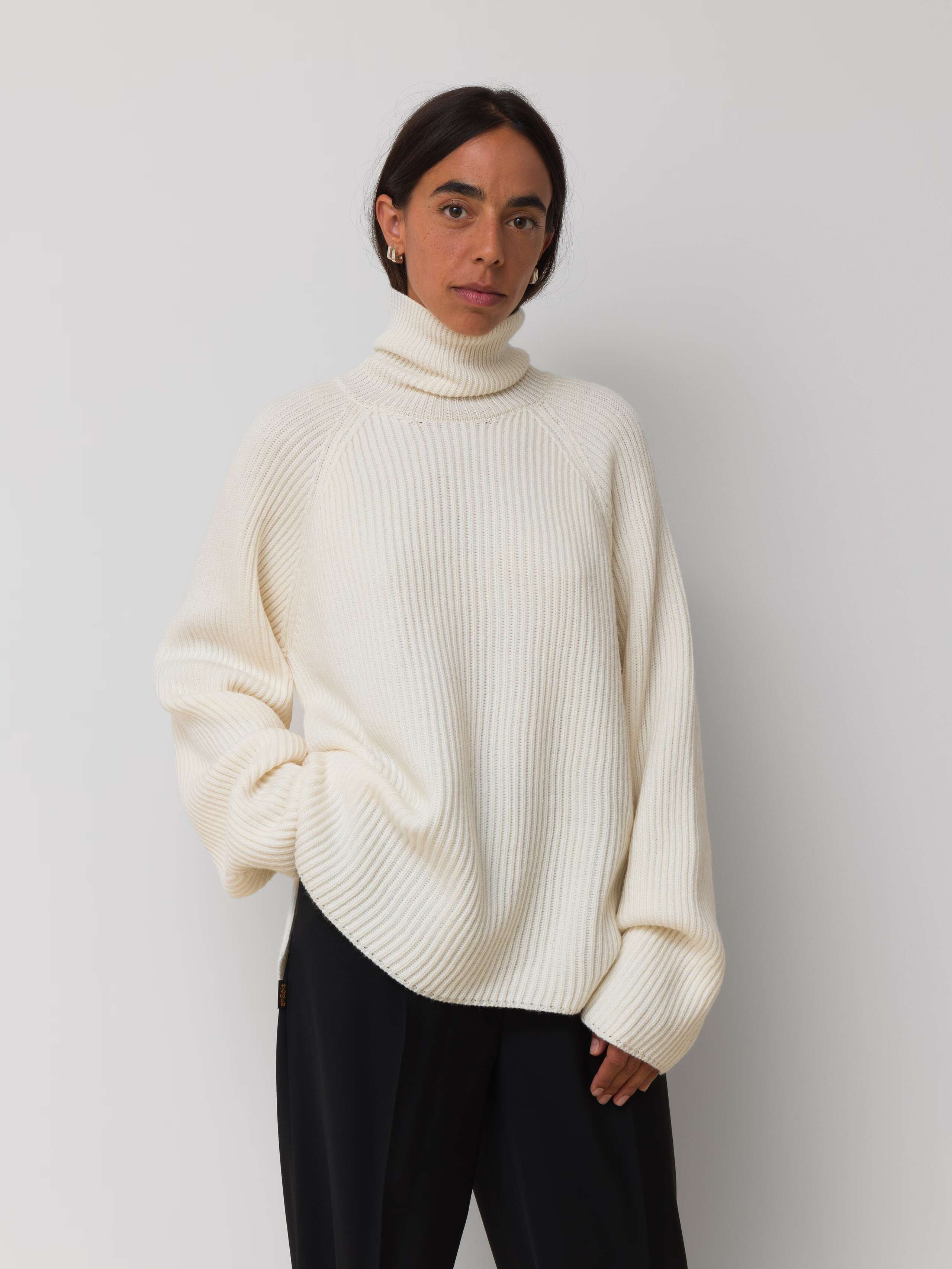 Picture of a female model wearing an off white turtleneck pullover