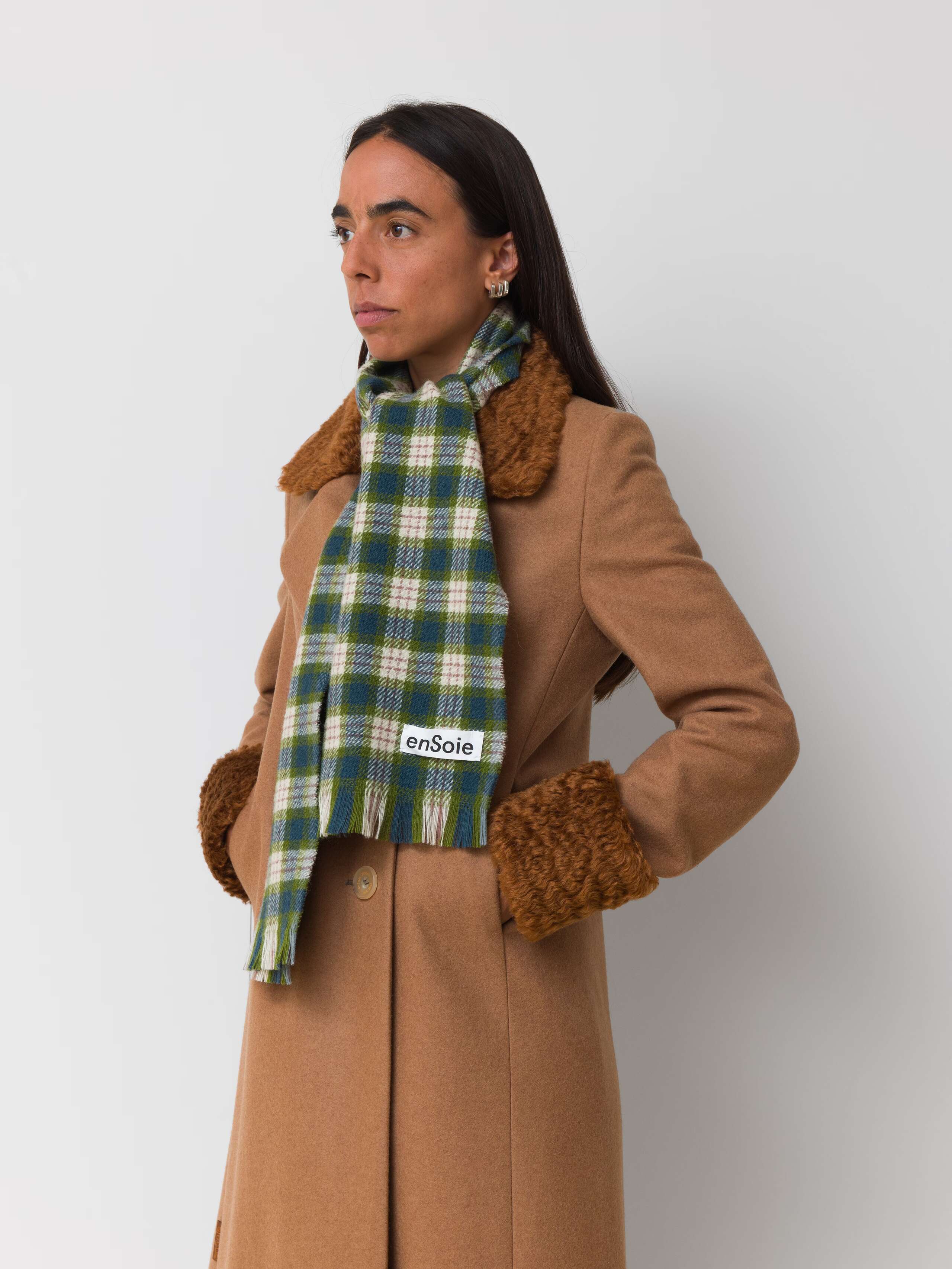 Picture of a female model wearing a beige wool coat in combination with a greenish wool scarf