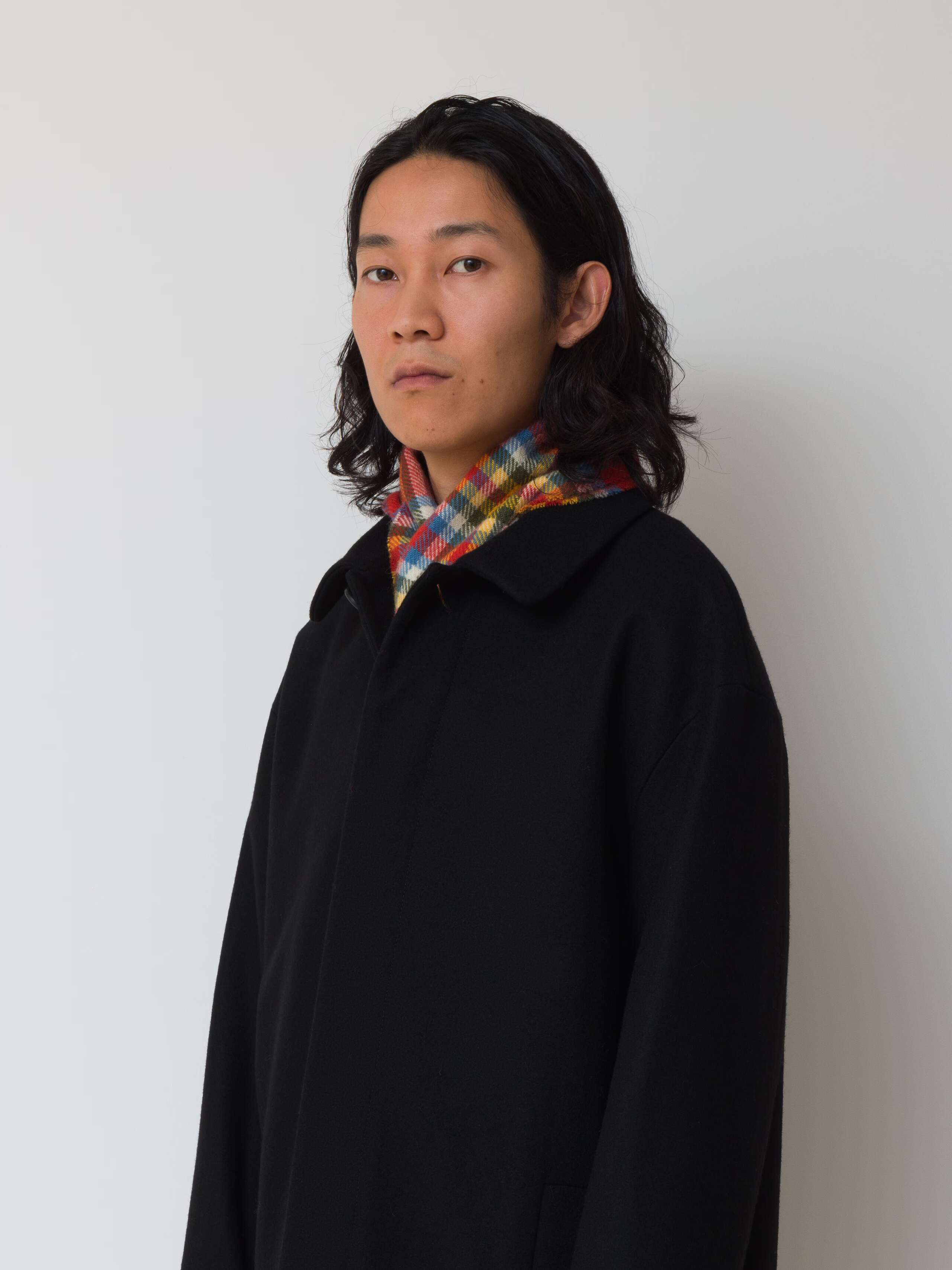 Picture of a male model wearing a black wool coat in combination with a colourful wool scarf